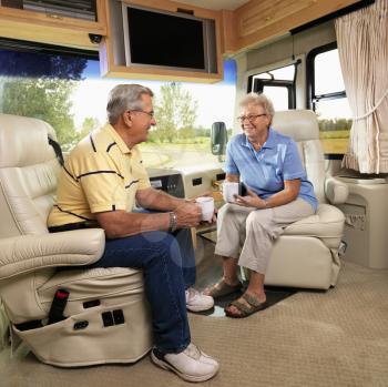 Royalty Free Photo of an Older Couple Sitting in an RV Holding Coffee Cups and Smiling