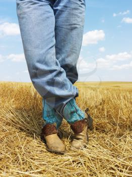 Royalty Free Photo of a Cowboy Standing in Harvested Crop Field Wearing Cowboy Boots