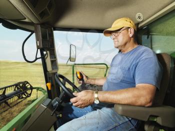 Royalty Free Photo of a Farmer Driving a Combine and Harvesting Crop