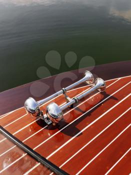 Royalty Free Photo of a Dual Chrome Trumpet Horn on a Wooden Boat Floating in Water