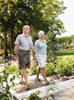 Royalty Free Photo of an Older Couple Holding Hands and Walking Outdoors in a Park