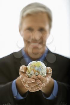 Royalty Free Photo of a Businessman Holding Out a Small Globe