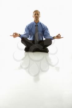 Royalty Free Photo of a Middle-aged Businessman Meditating in a Yoga Lotus Pose on the Floor