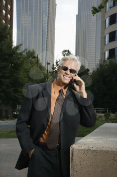 Royalty Free Photo of a Middle-aged Businessman in Sunglasses Talking on a Cellphone Outdoors