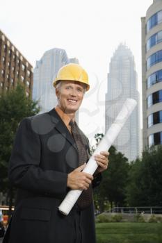 Royalty Free Photo of a Businessman Wearing a Hard Hat Holding Blueprints