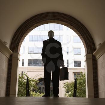Royalty Free Photo of a Businessman Standing in an Archway Holding a Briefcase
