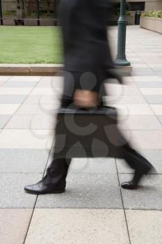 Royalty Free Photo of a Businessman Walking Outdoors With a Briefcase