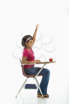 Royalty Free Photo of a Girl Sitting in a School Desk Raising Her Hand