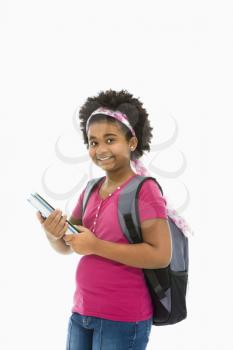 African American girl holding books and wearing backpack smiling at viewer.