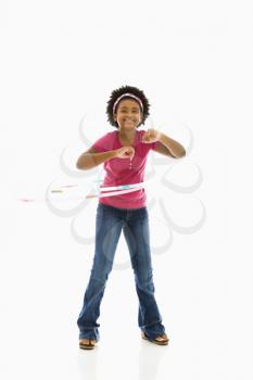 African American girl playing with hula hoop and smiling at viewer.