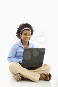 Royalty Free Photo of an African American Girl Sitting on the Floor Using a Laptop and Smiling