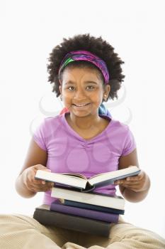 Royalty Free Photo of a Girl Sitting With a Stack of Books Smiling