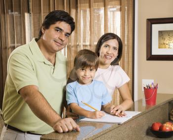 Royalty Free Photo of a Family of Three Standing in a Kitchen Posing with Homework on the Counter