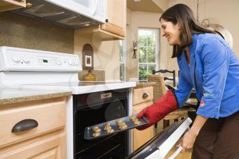 Royalty Free Photo of a Woman Putting Cookies into the Oven