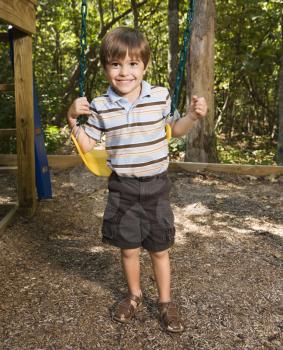 Royalty Free Photo of a Boy Standing By a Swing Set Smiling