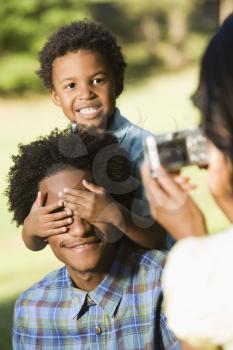 Royalty Free Photo of a Woman Photographing Husband and Son in a Park with a Digital Camera