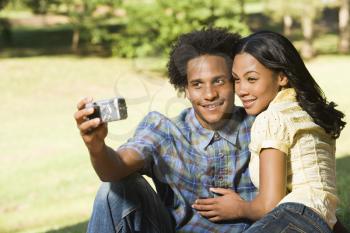 Royalty Free Photo of a Happy Smiling Couple Taking Pictures Together in a Park With a Digital Camera