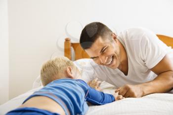 Royalty Free Photo of a Father and Son Playing in Bed 