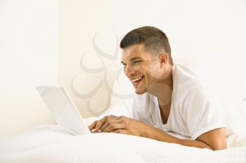 Royalty Free Photo of a Man Lying in Bed on a Laptop