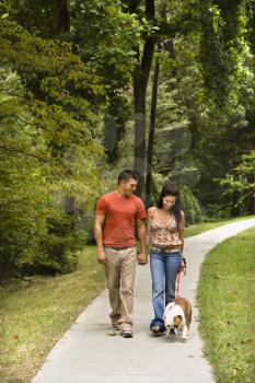Royalty Free Photo of a Couple Walking an English Bulldog in the Park
