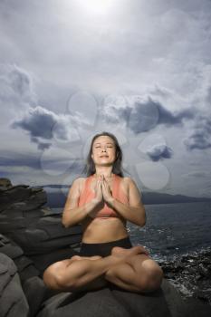 Royalty Free Photo of a Woman Sitting on a Rock by the Ocean in a Lotus Pose With Eyes Closed in Maui, Hawaii