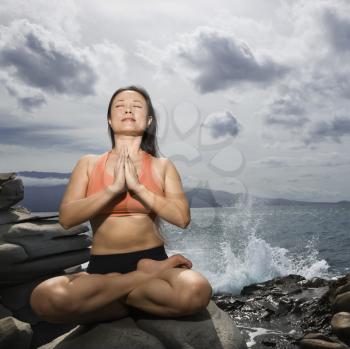 Royalty Free Photo of a Woman Sitting on a Rock in Lotus Pose in Maui, Hawaii