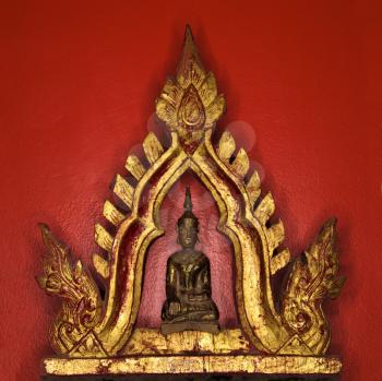 Royalty Free Photo of a Golden Buddha Statue Against a Red Wall
