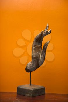 Royalty Free Photo of a Carved Hand Sculpture from Thailand Against Orange Wall