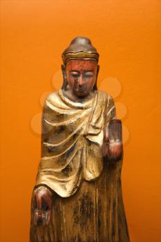 Royalty Free Photo of a Wooden Buddha Statue Gesturing With One Hand Up and One Hand Down
