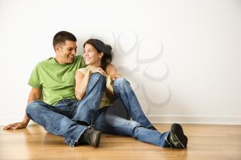 Royalty Free Photo of a Couple Sitting Together on Hardwood Floor at Home Smiling
