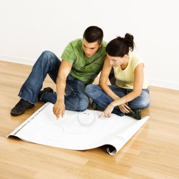 Royalty Free Photo of an Attractive Young Couple Looking at House Plans