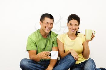 Royalty Free Photo of a Couple Sitting on the Floor Drinking Coffee and Smiling