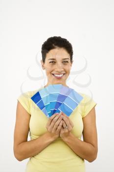 Royalty Free Photo of a Pretty Smiling Woman Holding Paint Sample Cards in Front of a White Wall