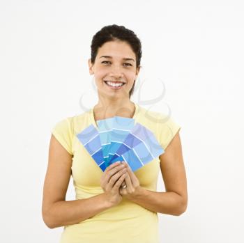 Pretty woman smiling holding out paint sample cards.