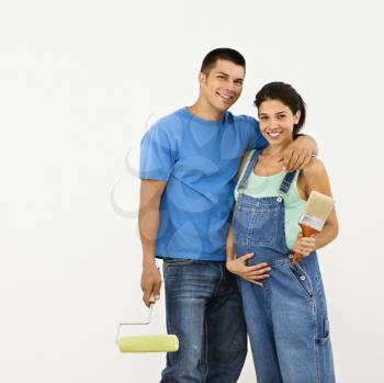 Royalty Free Photo of a Couple Expecting a Baby Holding Paintbrushes and Smiling
