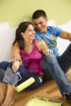 Royalty Free Photo of a Couple Sitting on the Floor Smiling Taking a Break From Painting