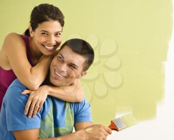 Royalty Free Photo of a Happy Smiling Couple Painting the Interior Wall at Home