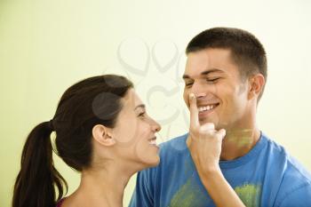 Royalty Free Photo of a Playful Smiling Woman Putting Paint on a Man's Nose