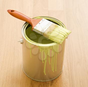 Royalty Free Photo of a Paintbrush Resting on a Paint Can on Wood Floor