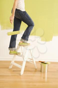 Royalty Free Photo of a Woman Climbing a Stepladder Holding a Paint Roller