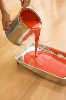 Royalty Free Photo of a Woman Pouring Red Paint From a Can into a Tray
