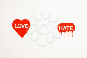 Heart with love painted on wall next to hate with drippings.