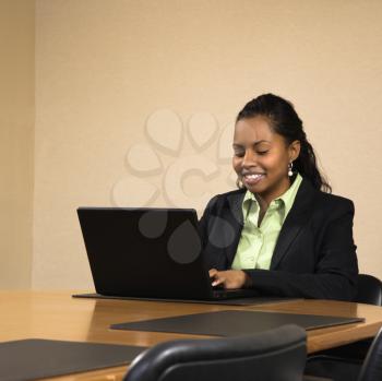 Royalty Free Photo of a Businesswoman Sitting at a Conference Table Typing on a Laptop