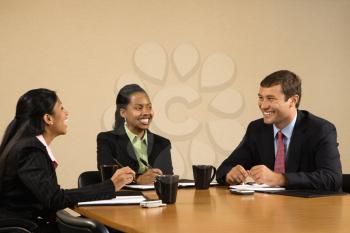 Royalty Free Photo of Businesspeople Sitting at a Conference Table Talking and Smiling