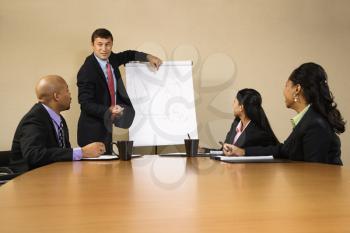 Businesspeople sitting at conference table  while businessman gives presentation.