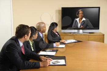 Royalty Free Photo of Businesspeople Sitting at a Conference Table Looking at a Flat Screen Display