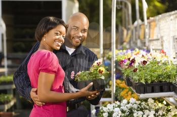 Royalty Free Photo of a Smiling Couple Picking Flowers at a Plant Market