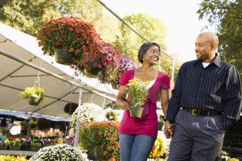 Royalty Free Photo of a Couple Picking Out Flowers at an Outdoor Plant Market Walking and Holding Hands