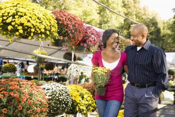 Royalty Free Photo of Happy Smiling Couple Picking Out Flowers at an Outdoor Plant Market Walking and Holding Hands