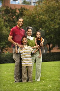 Royalty Free Photo of a Family Standing in a Park Smiling